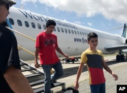 Fourteen-year-old Hermelindo Juarez, right, and his father, Deivin Juarez, step off a chartered flight from the U.S., Tuesday, July 10, 2018 in Guatemala City, Guatemala, after the two were deported.