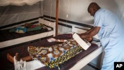 In this Aug. 28, 2014, photo, Aminatou Bello a 24-year-old Muslim, who was attacked by an Anti-Balaka, lies on a bed in Boda, Central African Republic. More than 5,000 people have died in sectarian violence in the Central African Republic since December, according to an Associated Press tally. (AP Photo/Sylvain Cherkaoui)