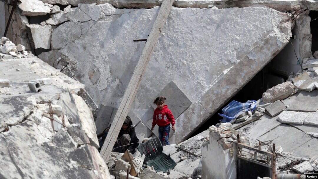 FILE - A Syrian woman cries as her wounded child lies on an operating table following artillery fire on the regime-held city of Aleppo, March 21, 2021.