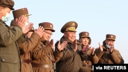 Ri Pyong Chol, the senior leader overseeing the test, and other military officials applaud after the launch of a new tactical guided projectile, March 25, 2021, in this photo released March 26, 2021, by the Korean Central News Agency in Pyongyang.