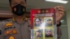 A Central Sulawesi Regional Police spokesperson shows a photo of Ahmad Gazali, bottom left, also known as Ahmad Panjang, that is displayed on a wanted poster along with other militant suspects, during a news conference in Palu, Indonesia, Jan. 4, 2022.