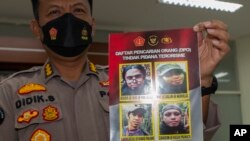 A Central Sulawesi Regional Police spokesperson shows a photo of Ahmad Gazali, bottom left, also known as Ahmad Panjang, that is displayed on a wanted poster along with other militant suspects, during a news conference in Palu, Indonesia, Jan. 4, 2022.