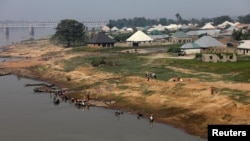 FILE - People are seen by the bank of Benue River in Makurdi, Nigeria, Nov. 29, 2018. Massive flooding is expected this month on the Niger and Benue rivers. 