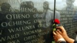 FILE - A woman puts flowers in front of the memorial with the names of the 213 people who died during the 1998 U.S. Embassy bomb blast, in Nairobi, Kenya, Aug. 7, 2002.