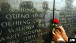 FILE - A woman puts flowers in front of the memorial with the names of the 213 people who died during the 1998 U.S. Embassy bomb blast, in Nairobi, Kenya, Aug. 7, 2002.