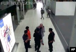 In this image made from airport closed circuit television video and provided by Fuji Television, Kim Jong Nam, exiled half-brother of North Korea's leader Kim Jong Un, gestures towards his face while talking to airport security and officials at Kuala Lump