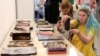 Відвідувачі "Книжкового арсеналу" фотографують книги, пошкоджені внаслідок російського обстрілу друкарні у Харкові у 2024 році. Фото: Anatolii Stepanov /AFP