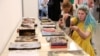 Visitors take pictures of damaged books of the Kharkiv publishing house, which were destroyed by Russian shelling on May 23, during the opening of the annual publisher's forum "Book Arsenal" in Kyiv, on May 30, 2024, amid the Russian invasion in Ukraine. 