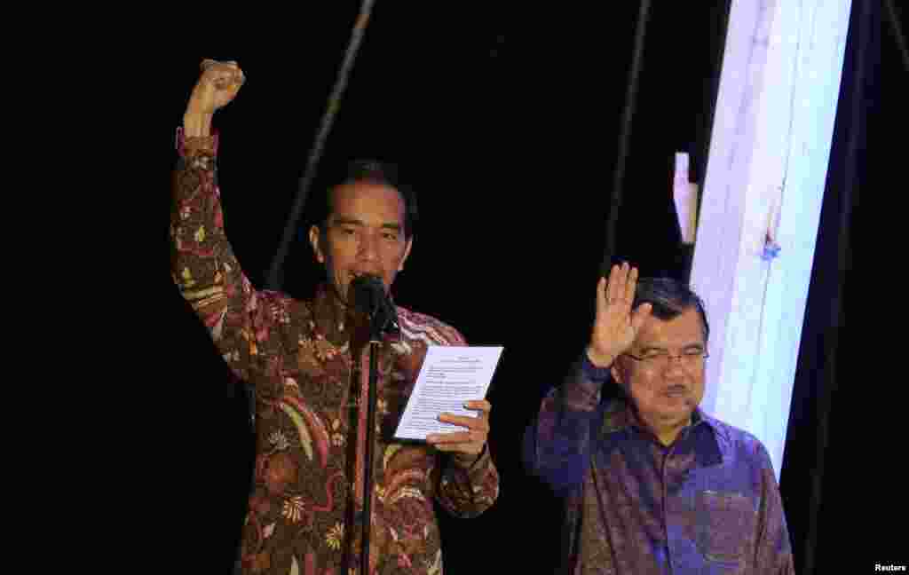 Presiden Indonesia terpilih Joko &quot;Jokowi&quot; Widodo mengangkat tangan saat menyampaikan pidato kemenangan, didampingi Wakil Presiden terpilih Jusuf Kalla, di atas kapal phinisi di Pelabuhan Sunda Kelapa (22/7). (Reuters/Beawiharta)