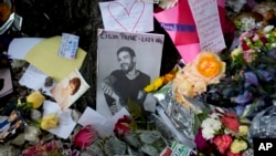 FILE - A picture of former One Direction singer Liam Payne sits surrounded by flowers and candles as fans gather outside the hotel where he was found dead after falling from a balcony in Buenos Aires, Argentina, Oct. 17, 2024. 