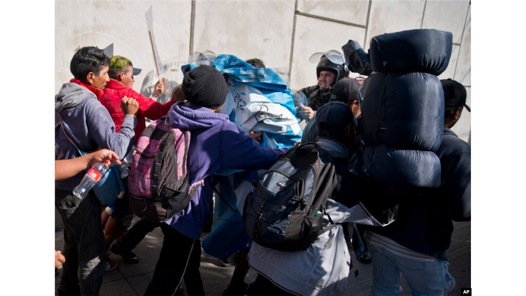 Migrants push past Mexican police at the Chaparral border crossing in Tijuana, Mexico, Sunday, Nov. 25, 2018, as they try to reach the United States.