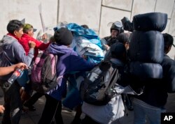 Migrants push past Mexican police at the Chaparral border crossing in Tijuana, Mexico, Sunday, Nov. 25, 2018, as they try to reach the United States.