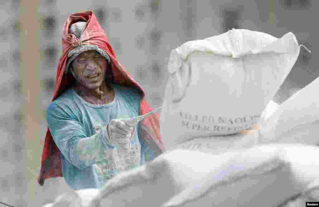 A worker unloads kaolin powder from a wooden ship at Sunda Kelapa harbour in Jakarta, Indonesia.
