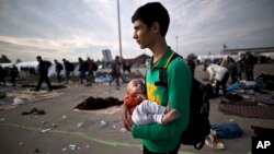 FILE - Afghan refugee Rasoul Nazari, 15, holds his 10-month-old nephew Imran after crossing the border between Hungary and Austria in Nickelsdorf, Austria. 