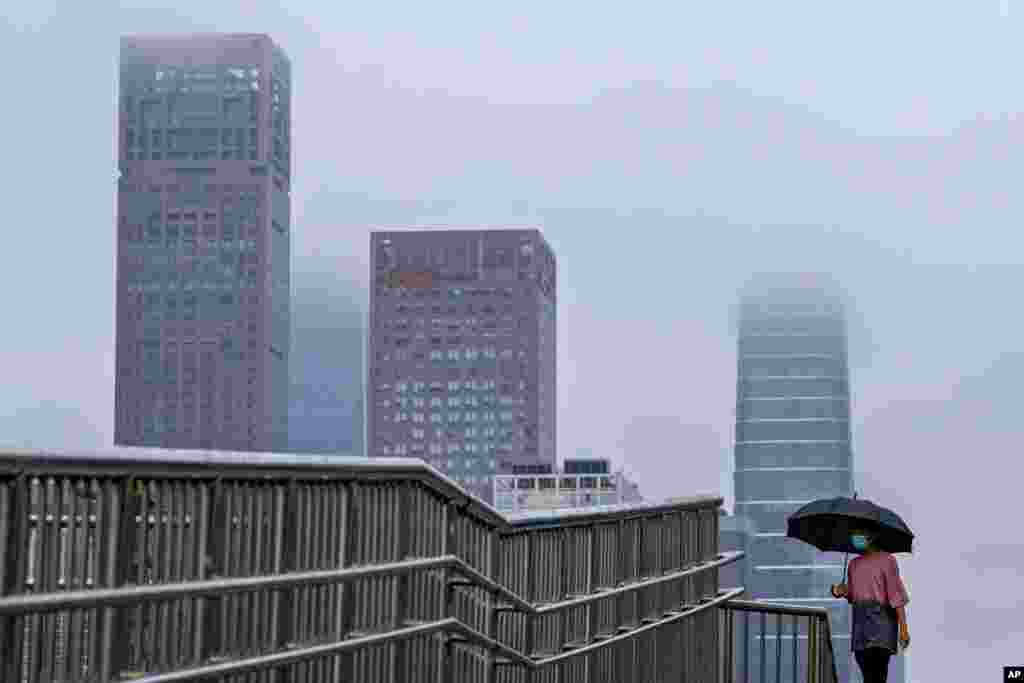 A woman walks on a bridge on a rainy day in the Central Business District in Beijing, China.