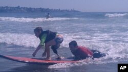 Shaun McLaughlin, 6, who was born without a right foot, gives surfing a try under the watchful eye of AmpSurf volunteers and instructors.