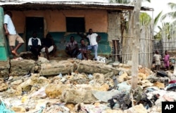 FILE - Local residents look at rubble and other items washed close to their doorstep when Cyclone Kenneth struck, in Pemba city on the northeastern coast of Mozambique, April, 27, 2019.