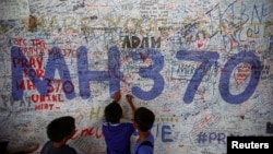 Anak-anak menulis pesan harapan bagi penumpang pesawat Malaysia Airlines bernomor penerbangan MH370 di bandara internasional Kuala Lumpur. (Reuters/Samsul Said)