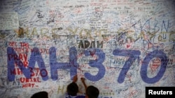 Photo d'archives : Des enfants écrivant des messages d'espoir, à l'aéroport international de Kuala Lumpur le 14 juin 2014, pour les passagers du vol MH370 de la Malaysia Airlines disparu depuis le 8 mars 2014.