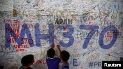 Anak-anak menulis pesan harapan bagi penumpang pesawat Malaysia Airlines bernomor penerbangan MH370 di bandara internasional Kuala Lumpur. (Reuters/Samsul Said)