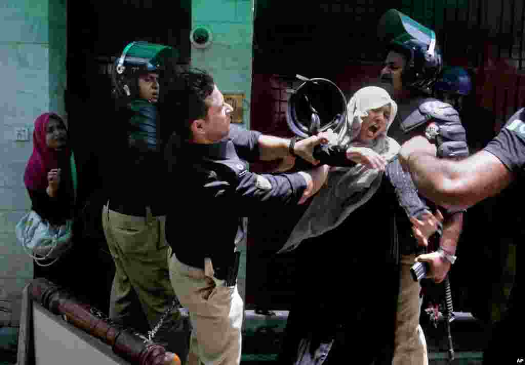 A police officer scuffles with a protester during clashes in Lahore, Pakistan. Police clashed with followers of an anti-Taliban cleric critical of the government in the eastern city, leaving at least seven people killed, officials said.