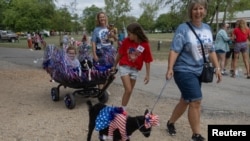 Leila Burleson, de 10 años, tira de su hermana Laiken, de 8, en una carreta, incluidos sus dos Cavalier King Charles Spaniels Hazel y Sadie en el esfile anual de mascotas celebrando el Día de la Independencia de EEUU en Bandera, Texas, el 4 de julio de 2024.