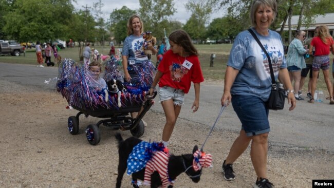 Leila Burleson, de 10 años, tira de su hermana Laiken, de 8, en una carreta, incluidos sus dos Cavalier King Charles Spaniels Hazel y Sadie en el esfile anual de mascotas celebrando el Día de la Independencia de EEUU en Bandera, Texas, el 4 de julio de 2024.