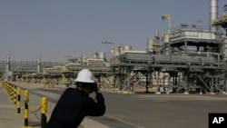 Seorang fotografer memotret ladang minyak Khurais, 50 km timur-timur laut Riyadh, Arab Saudi, 28 Juni 2021. (Foto: AP)
