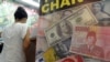 FILE - The U.S. dollar, Indonesian rupiah and Chinese renminbi currencies are displayed in the poster of a money exchange shop in Jakarta, June 12, 2013.