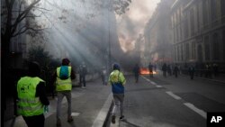 "Yellow vest" protesters walk toward a burning makeshift barricade during scuffles with riot police as they keep pressure on French President Emmanuel Macron's government, for the 13th straight weekend of demonstrations, in Paris, France, Feb. 9, 2019.