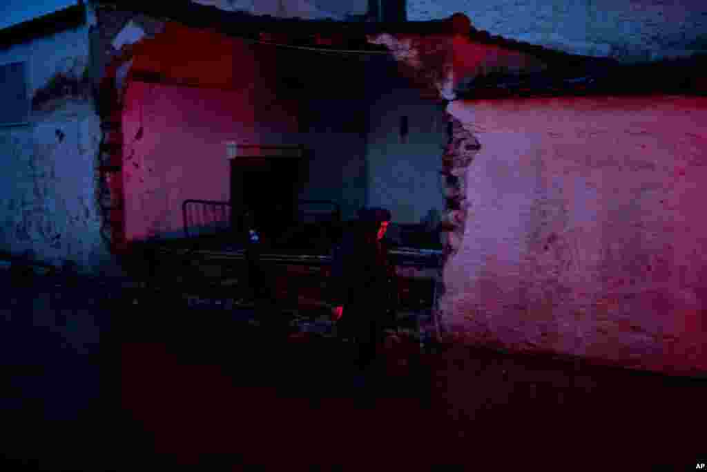 A elderly woman walks in front of a damaged house in the town of Mandra western Athens, Greece. Hopes were diminishing as darkness fell Friday for six people reported missing in deadly flash floods that struck near Athens, killing 16.