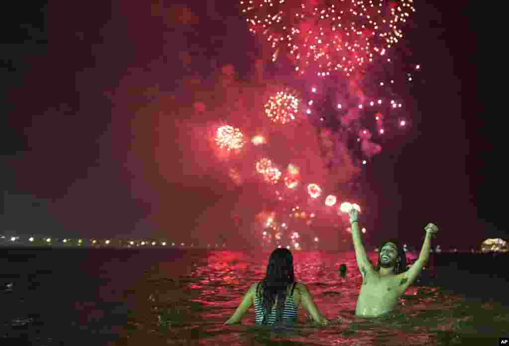 La gente observa los fuegos artificiales explotando sobre la playa de Copacabana durante las celebraciones de Nochevieja en Río de Janeiro, Brasil. (Foto AP)