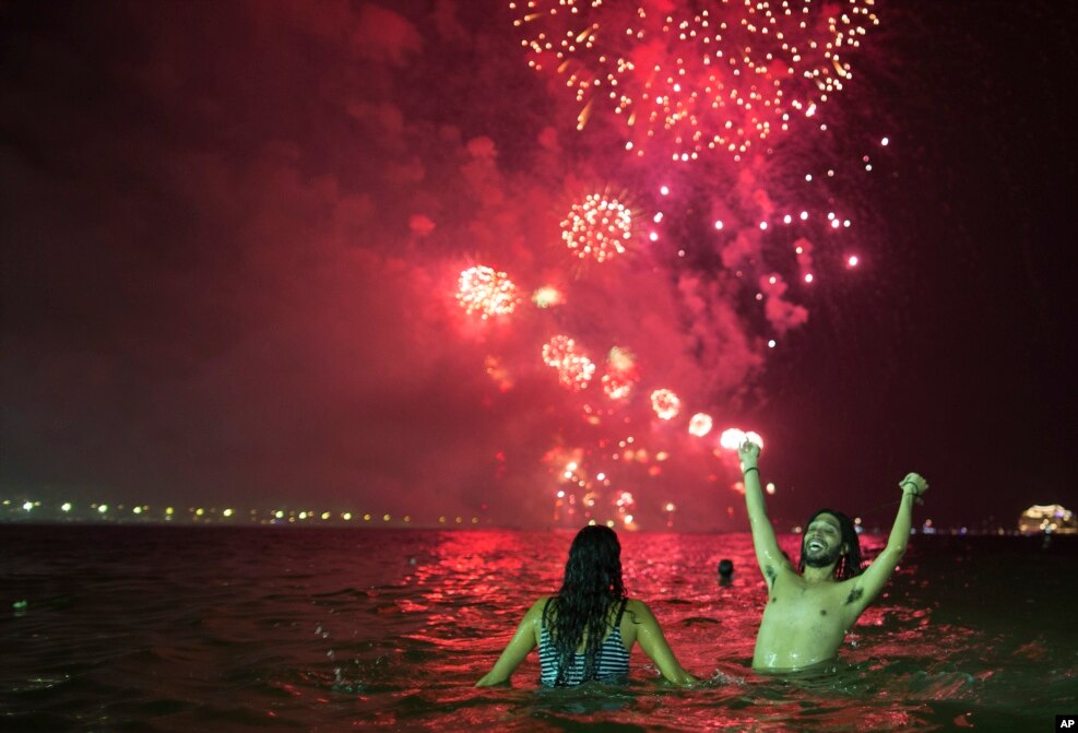 La gente observa los fuegos artificiales explotando sobre la playa de Copacabana durante las celebraciones de Nochevieja en Río de Janeiro, Brasil. (Foto AP)