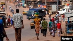 FILE - People walk as security forces traveling in a truck patrol a street in the Ivory Coast in Dec. 2010.