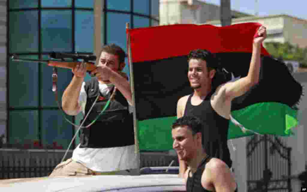 Libyan rebel fighters celebrate as they drive through Tripoli's Qarqarsh district . Libyan government tanks and snipers put up scattered, last-ditch resistance in Tripoli on Monday after rebels swept into the heart of the capital, cheered on by crowds hai