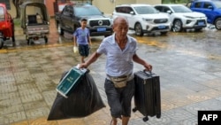 A local resident carries food and his luggage to a temporary shelter in a primary school ahead of the expected landfall of Super Typhoon Yagi in Wenchang, in southern China's Hainan province on Sept. 6, 2024.