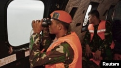 1일 에어아시아 사고 여객기 실종자들을 찾는 수색대가 헬리콥터 안에서 망원경으로 자바해를 내려다보고 있다.
