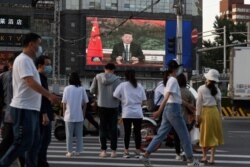 北京街头的行人观看电子屏幕上中国国家主席习近平通过视频在世卫大会视频开幕式上致辞。（2020年5月18日）