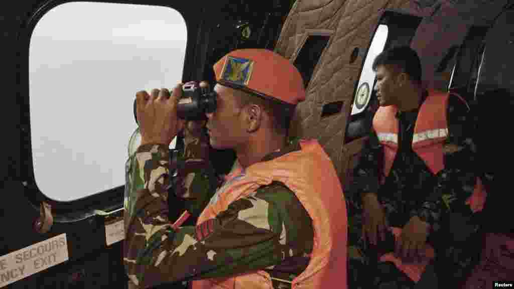 A crewmember of an Indonesian Air Force Super Puma helicopter of 6th Air Squadron uses a binocular to scan the horizon during a search operation for the victims of AirAsia Flight 8501 over the Java Sea, Jan. 1, 2015. 