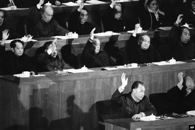 1981年12月13日，中国人大会议上，中国领导人表决通过赵紫阳（第一排左）总理的经济工作报告。第二排左起：胡耀邦、邓小平、李先念、陈云、华国锋。