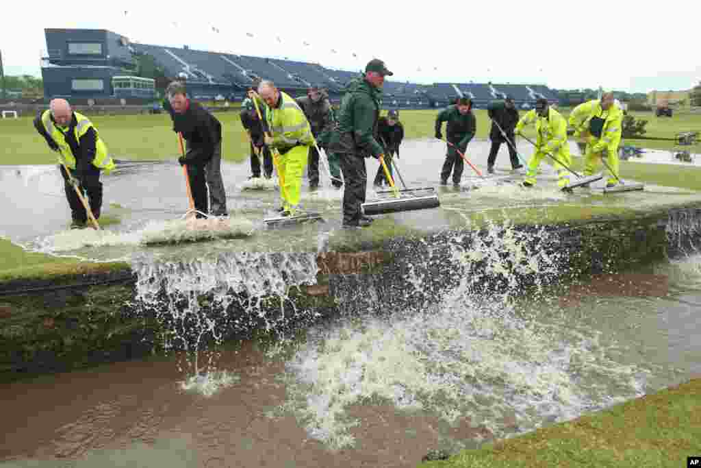 Grounds staff sweep floodwater into the Swilcan Burn after heavy rain delayed the start of the second round of the British Open Golf Championship at the Old Course, St. Andrews, Scotland.