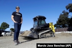 Built Robotics CEO Noah Ready-Campbell stands next to the company's self-driving track loader in San Francisco.