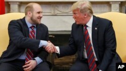 Presiden Donald Trump berjabat tangan dengan Joshua Holt, yang baru baru ini dibebaskan dari sebuah tahanan di Venezuela, di Ruang Oval, Gedung Putih, 26 Mei 2018, di Washington.