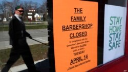 Un transeúnte camina frente a The Family Barbershop, una barbería cerrada debido a la pandemia en Grosse Pointe Woods, Michigan, el 2 de abril de 2020.