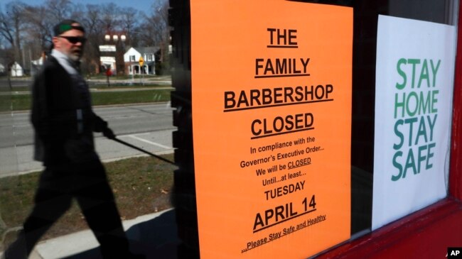 Un transeúnte camina frente a The Family Barbershop, una barbería cerrada debido a la pandemia en Grosse Pointe Woods, Michigan, el 2 de abril de 2020.