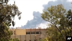 Smoke is seen after coalition air strikes in Tripoli, June 17, 2011