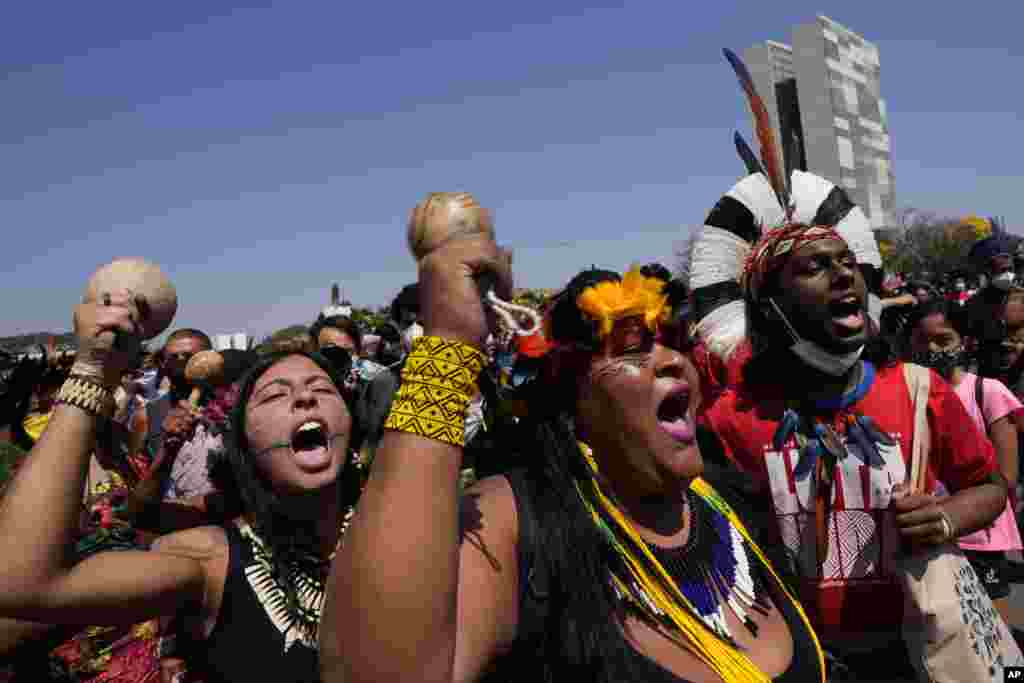 Indigenous protesters shout outside Planalto presidential palace in Brasilia, Brazil, Friday, Aug. 27, 2021. Indigenous are demanding the Supreme Court protect their land rights and reserves, asking justices to uphold their territorial rights in a landmark case that could open their lands to outside development by commercial interests. (AP Photo/Eraldo Peres)