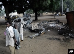 FILE - Children stand near the scene of an explosion a day after two female suicide bombers targeted a busy marketplace in Potiskum, Nigeria, Jan. 12, 2015.