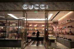 Personal de la tienda de lujo italiana Gucci usan máscaras en un centro comercial en Beijing, China, el jueves, 20 de febrero de 2020.