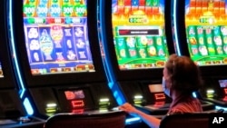 FILE - A woman plays a slot machine at the Golden Nugget casino in Atlantic City, New Jersey, July 2, 2020.